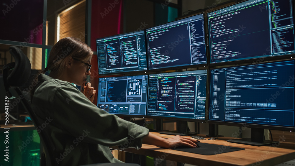 女性网络安全专家在黑暗办公室用六显示器台式电脑编写代码。C