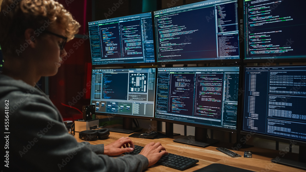 年轻的高加索男子在黑暗办公室的专业六监视器上编写代码。男性网络安全