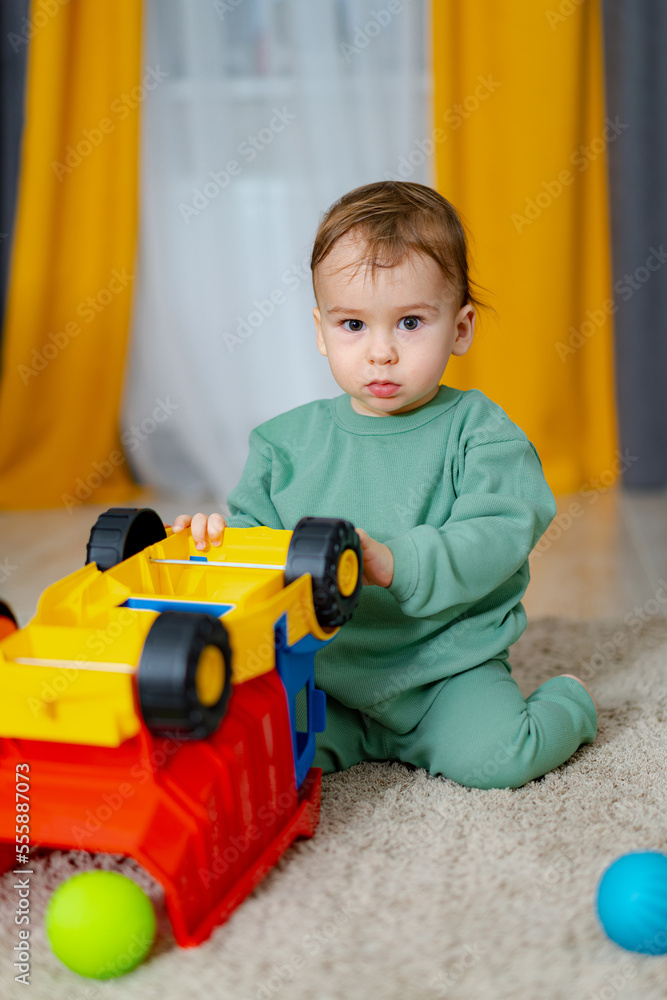小男孩在家里玩室内玩具。微笑的小男孩玩玩具车。早期发展