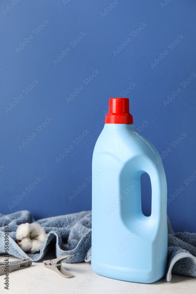 Laundry detergent and towel with beautiful flower on table against blue background