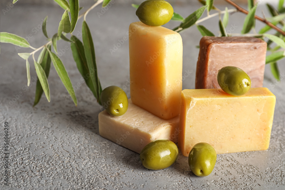 Soap bars with green olives and tree branch on dark background, closeup