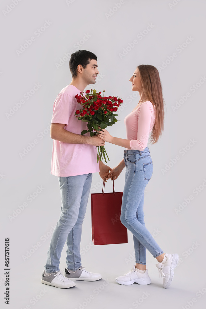 年轻情侣爱上玫瑰和浅色背景的包包。情人节庆祝活动
