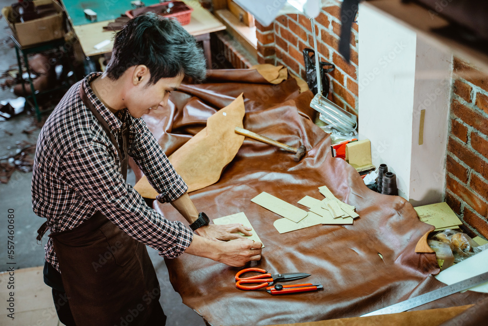 亚洲围裙工匠在车间里用皮革紧贴图案纸工作