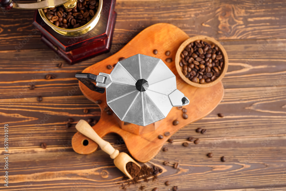 Board with geyser coffee maker, scoop and plate of beans on wooden background