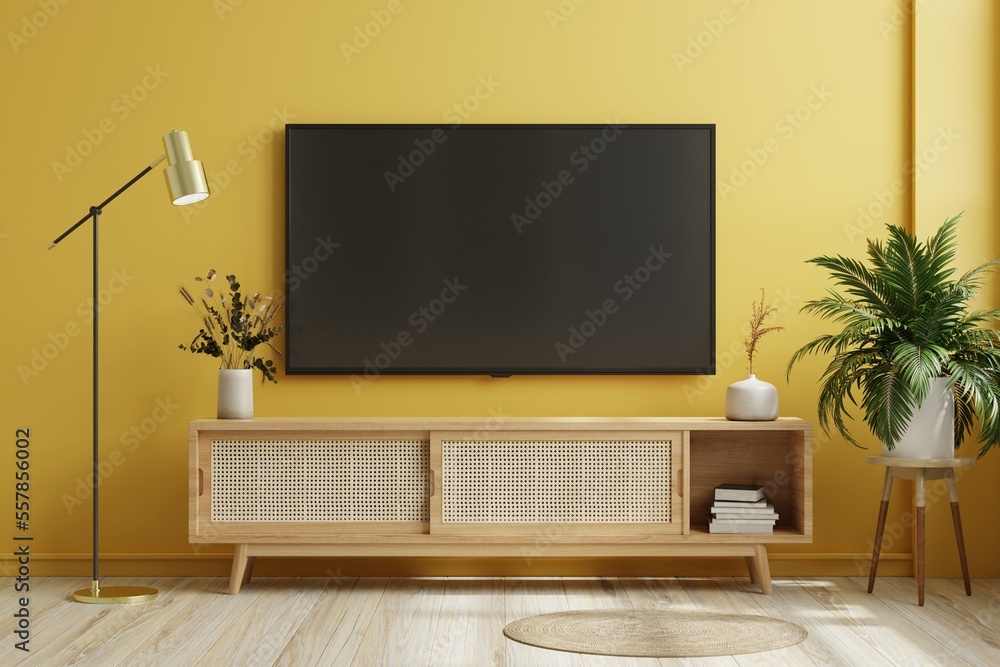 黄色照明墙上现代客厅橱柜上的电视。