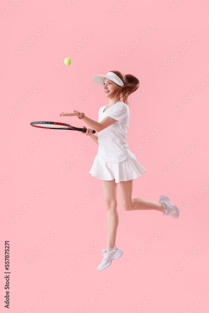 粉色背景下球拍和球跳跃的年轻女子网球运动员