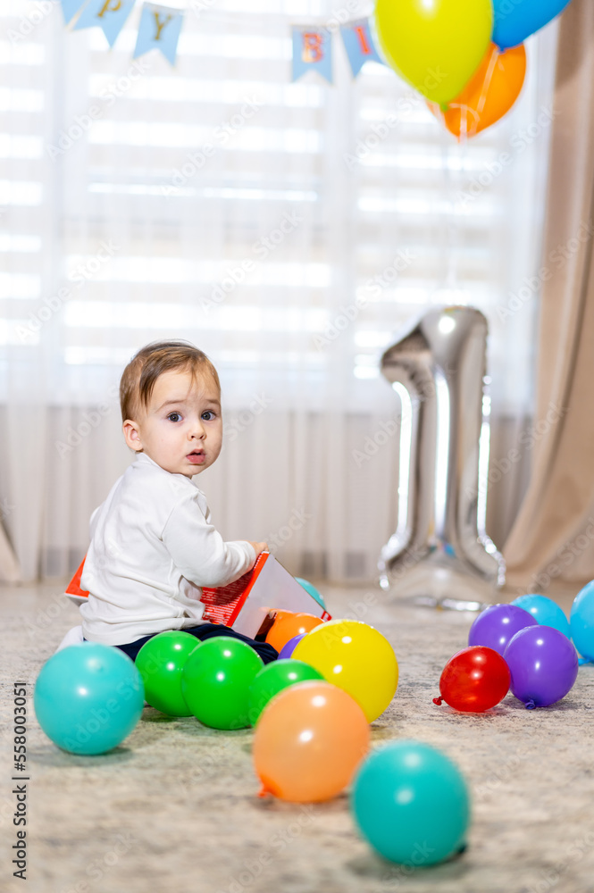 First birthday party. One year old with colorful balloons. Birthday celebration.