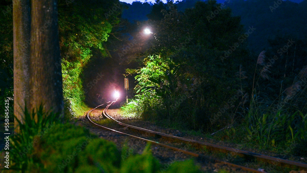 The train with the lights on is running through the mountains and forests. Sandiaoling Railway Stati