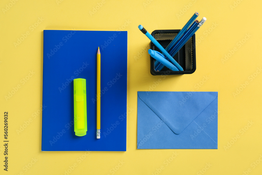 黄色背景的装有文具、笔记本和信封的支架