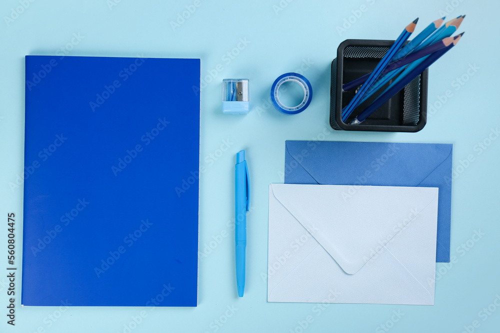 蓝色背景的装有文具、笔记本和信封的支架
