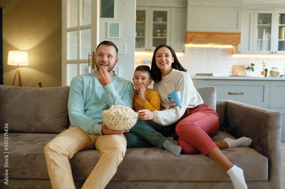 幸福的一家人坐在客厅沙发上看电影吃爆米花