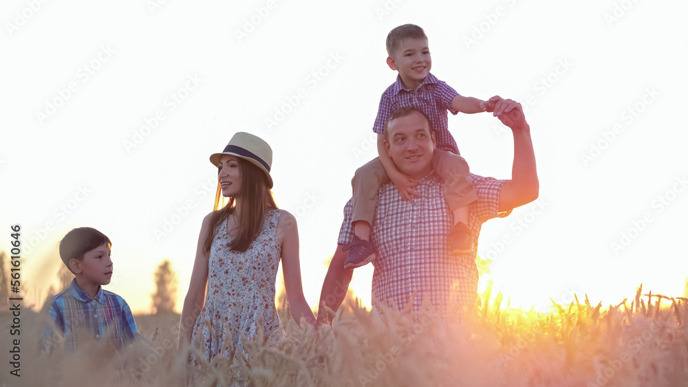 Excited family walks on wheat field together. Happy parents and siblings enjoy spending summer holid