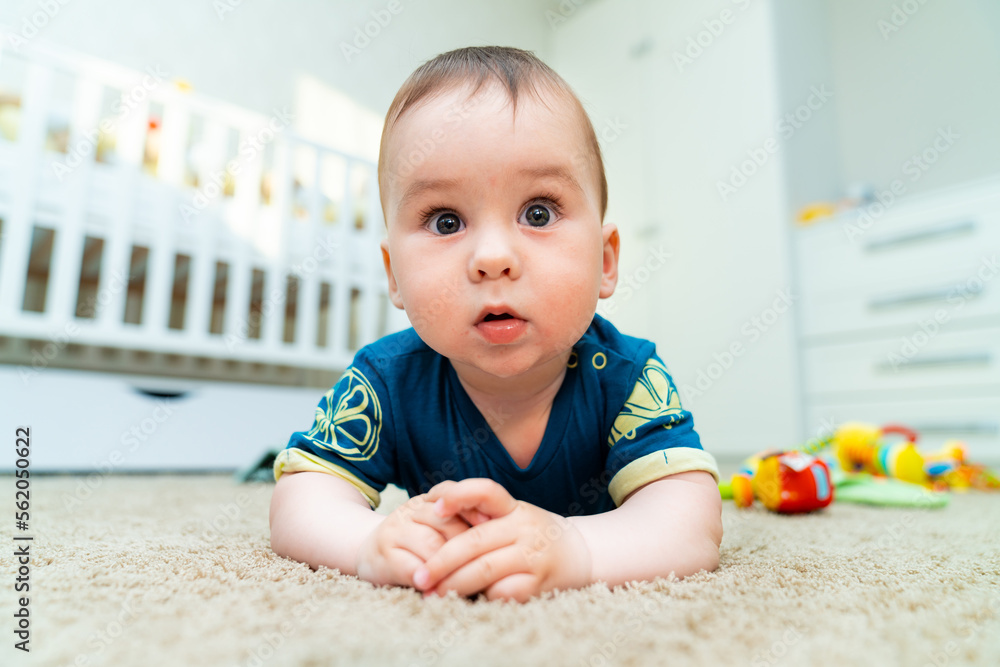 Cute happy baby boy playing toys in his child room. Beautiful baby crawls around the house