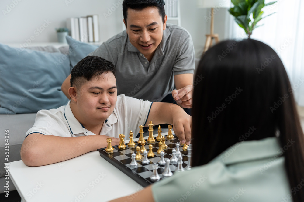 一对亚洲美女夫妇和他们的儿子在客厅里下棋。