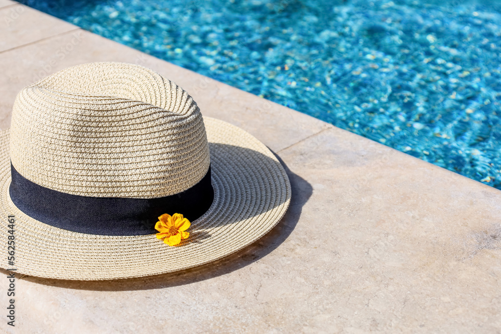 Summer hat with flower on edge of swimming pool, closeup