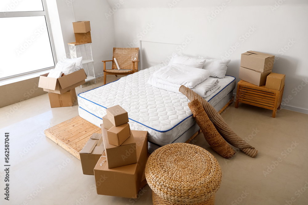 搬家当天卧室里有床、袋子和卷地毯的纸板箱