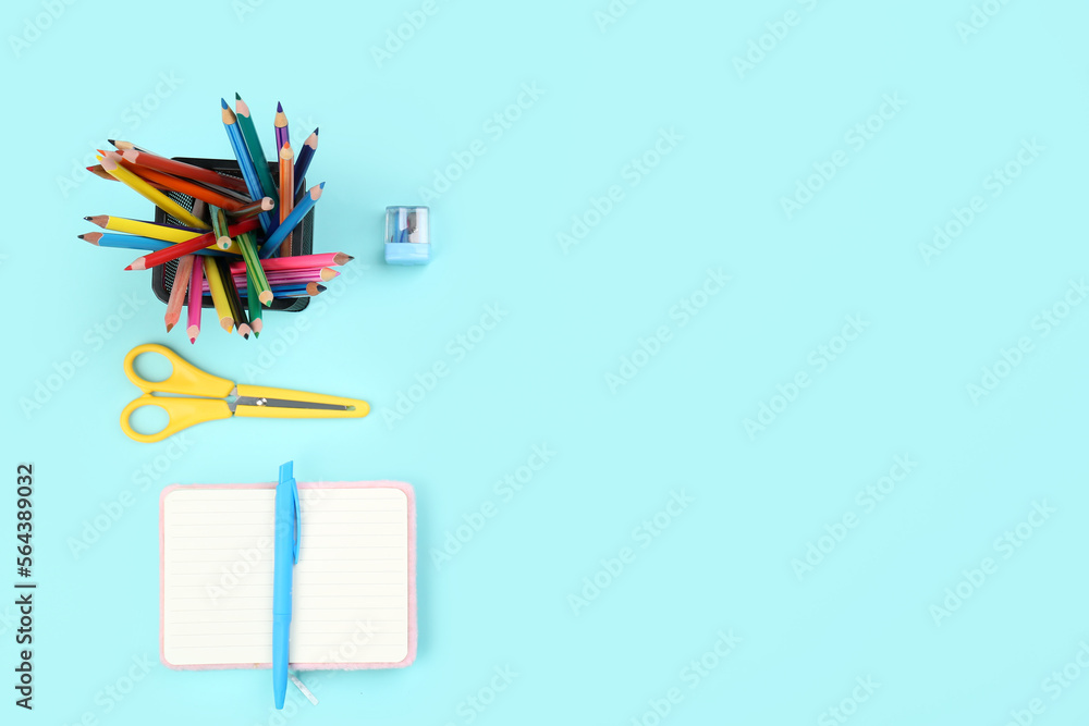 Holder with stationery and open notebook on blue background