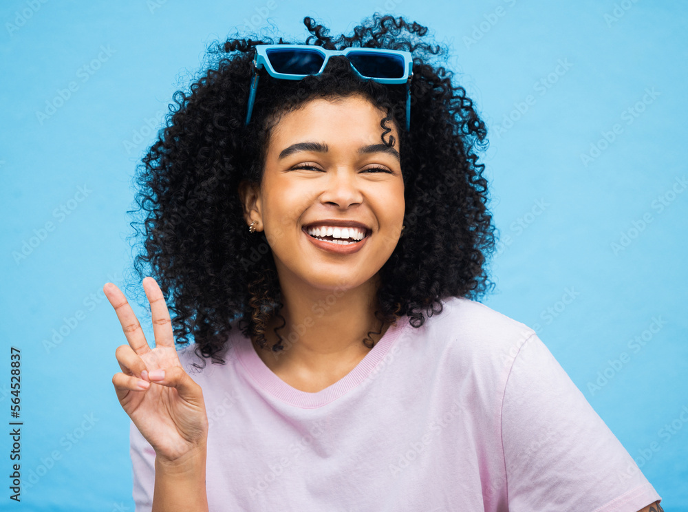 Black woman, happy smile and peace sign portrait of a model isolated with blue background in a studi