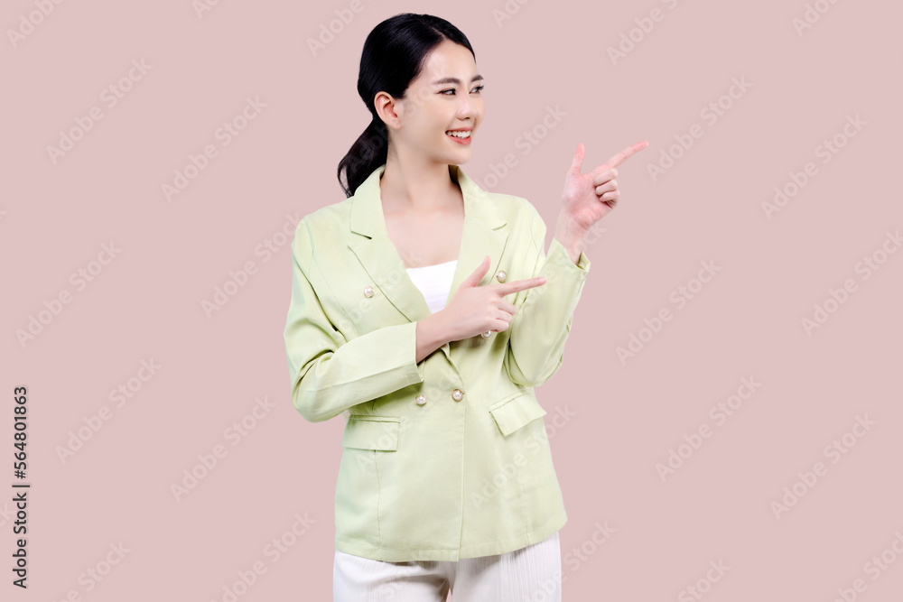 Cheerful excited young Asian woman pointing finger to side with copy space standing over isolated on