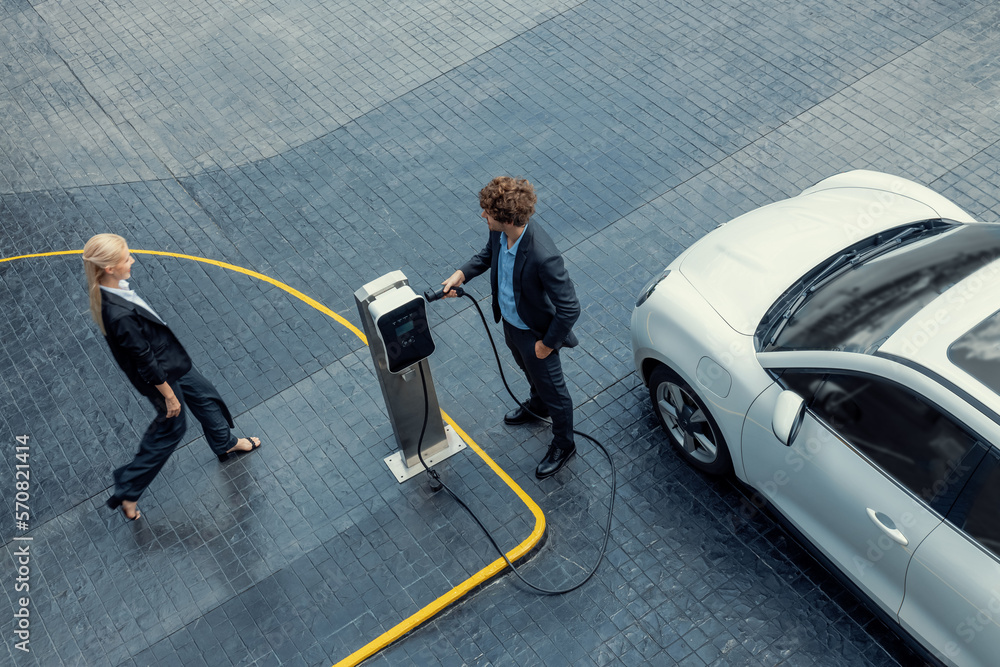 Aerial view progressive lifestyle of businesspeople with electric car connected to charging station 