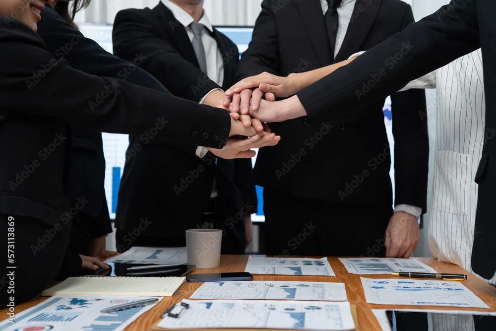 Closeup business team of suit-clad businessmen and women join hand stack together and form circle. C
