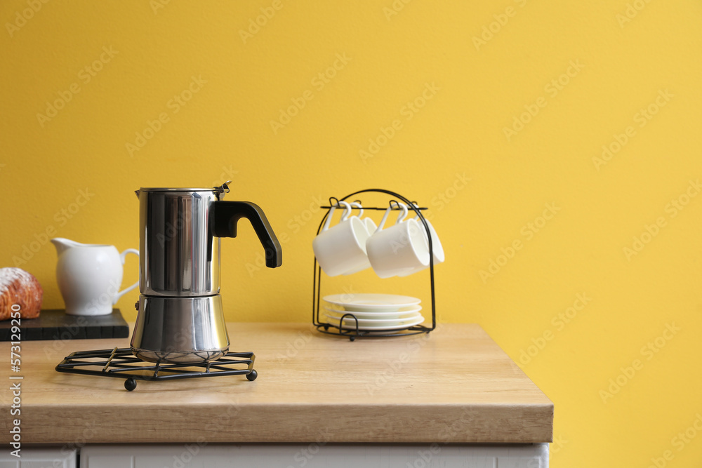 Grid with geyser coffee maker on kitchen counter near yellow wall
