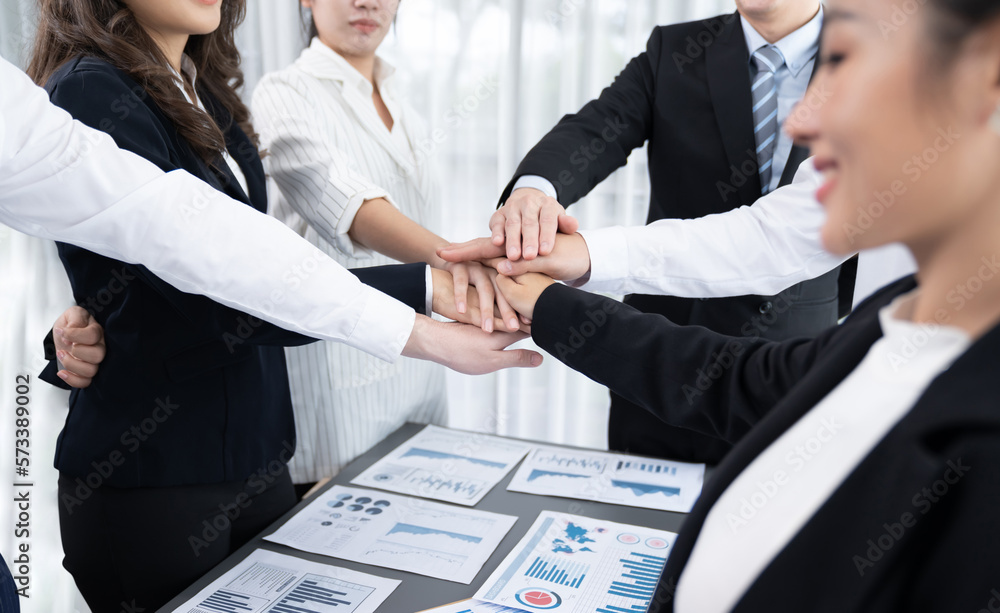 Closeup business team of suit-clad businessmen and women join hand stack together and form circle. C