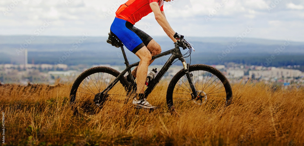 man cyclist biking of dry grass in mountain bike