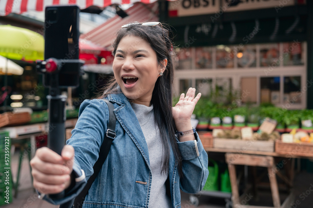 asian female blogger vlogger record vlog streaming video hold phone on selfie stick in open market u