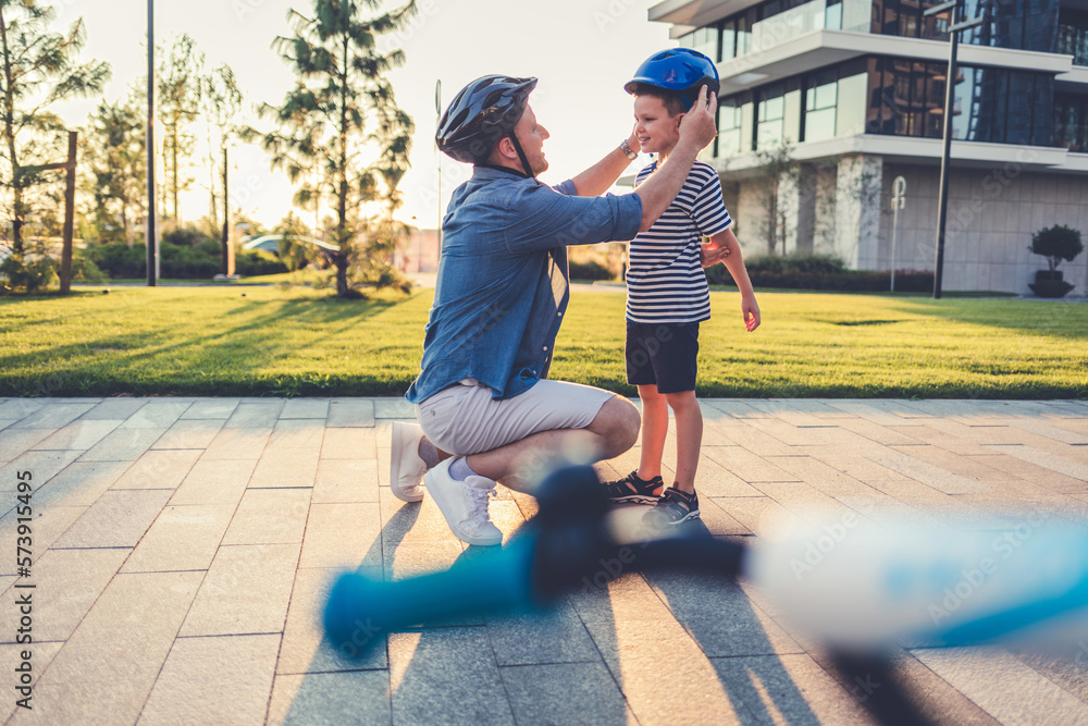 Stock photo of a father helping his son put on a bicycle helmet.