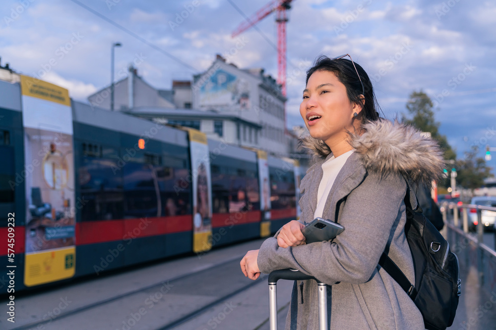 happiness asian carefree woman traveller waiting for city bus tram in Vienna Austria sunset,cheerful