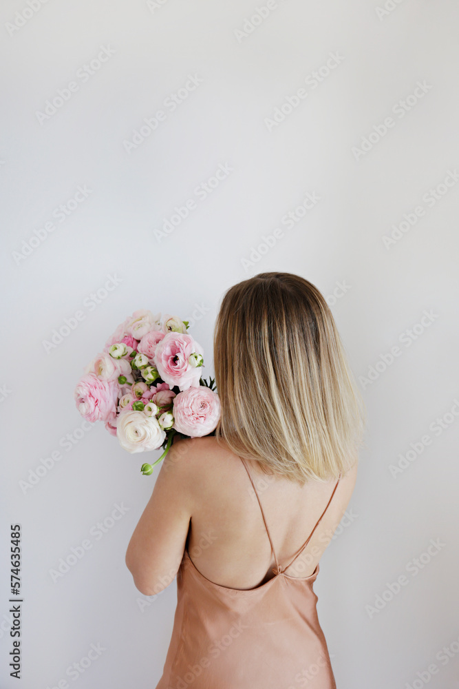 Conceptual portrait of young woman wearing minimalistic silk dress covering her face with lush butte