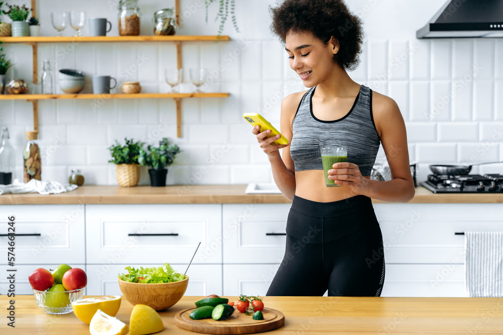 Healthy food concept. Positive slim brazilian or latino girl in sportswear, stand in a kitchen, prep
