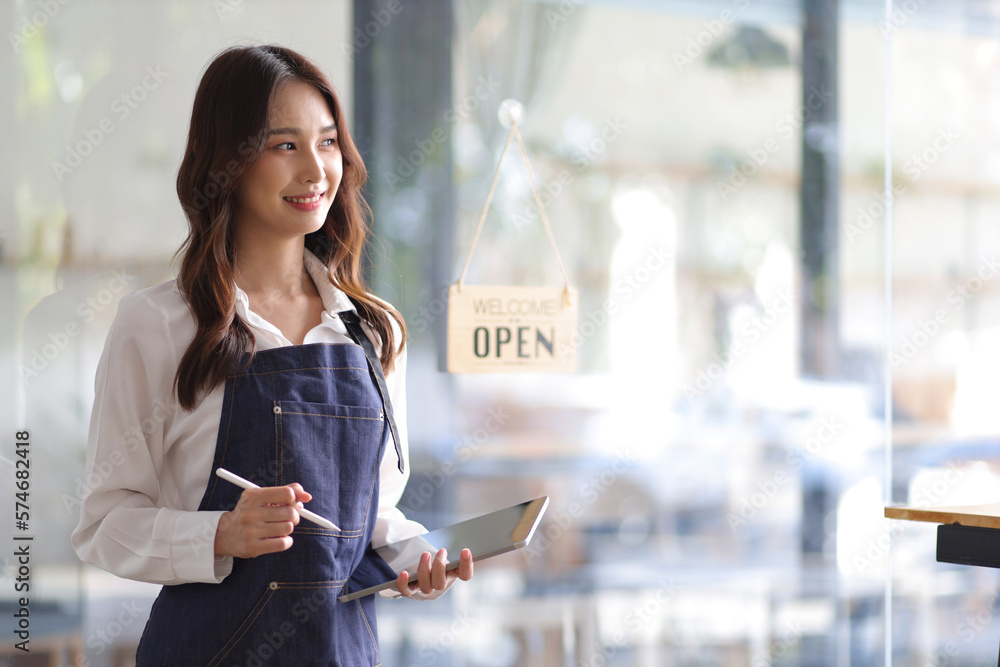 Portrait of a young female entrepreneur hanging a welcome sign in front of a coffee shop. Beautiful 