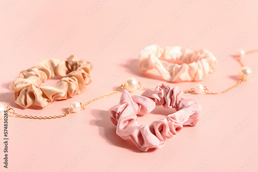 Silk scrunchies and necklace on pink background, closeup