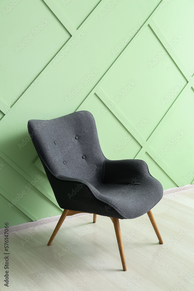 Modern grey armchair near green wall
