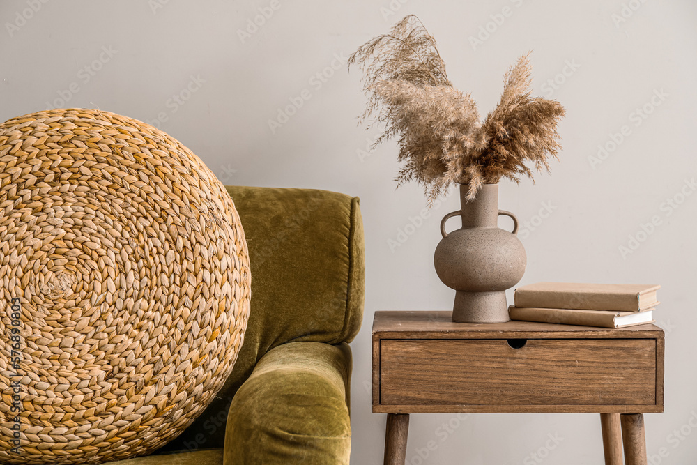 Vase with pampas grass and books on table in light living room