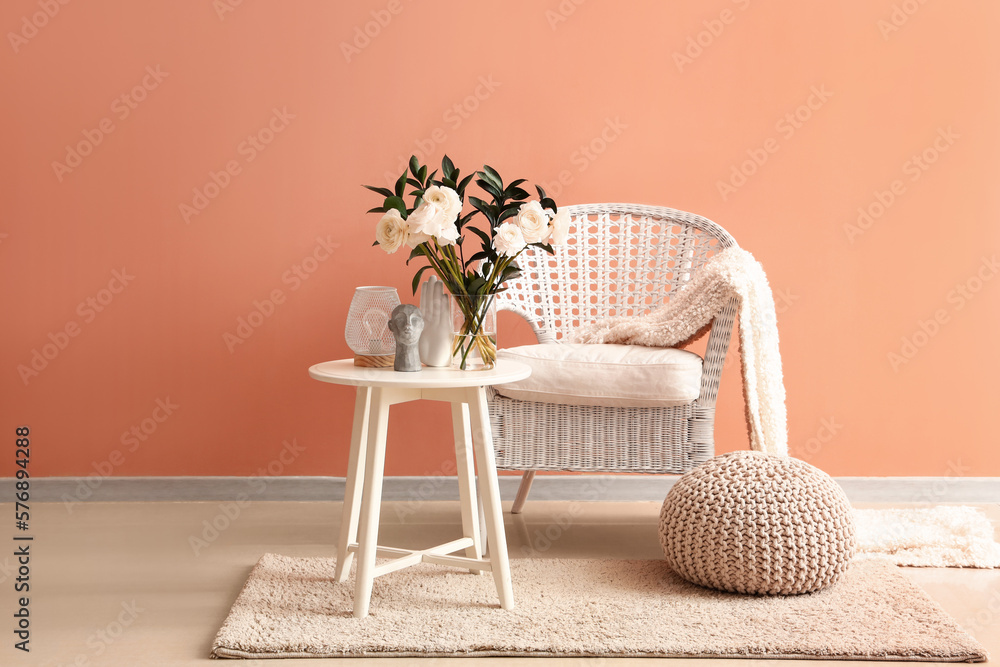 Vase with ranunculus flowers, lamp and decor on table in interior of living room