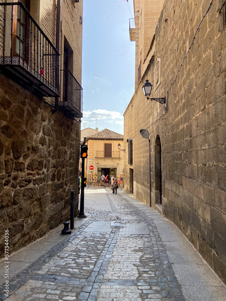 This photo captures a quaint street in a Spanish city, lined with old concrete buildings on either s