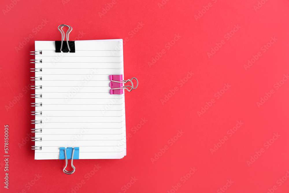 Notebook with binder clips on red background