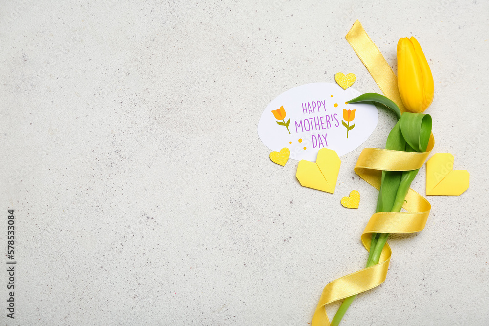 Composition with greeting card, tulip flower, ribbon and origami hearts on light background. Mother