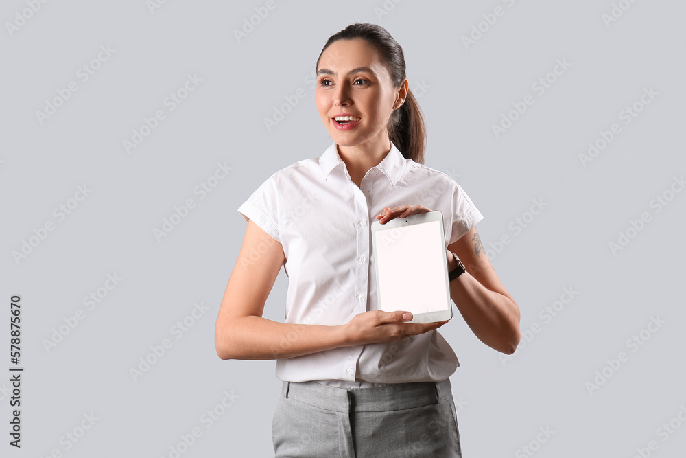 Female business consultant with tablet computer on grey background