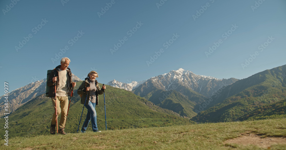 Mature caucasian couple on vacation, having a hike in spring mountains, spending time together after