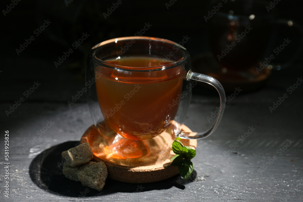 Cup of tasty green tea and cane sugar on dark wooden table
