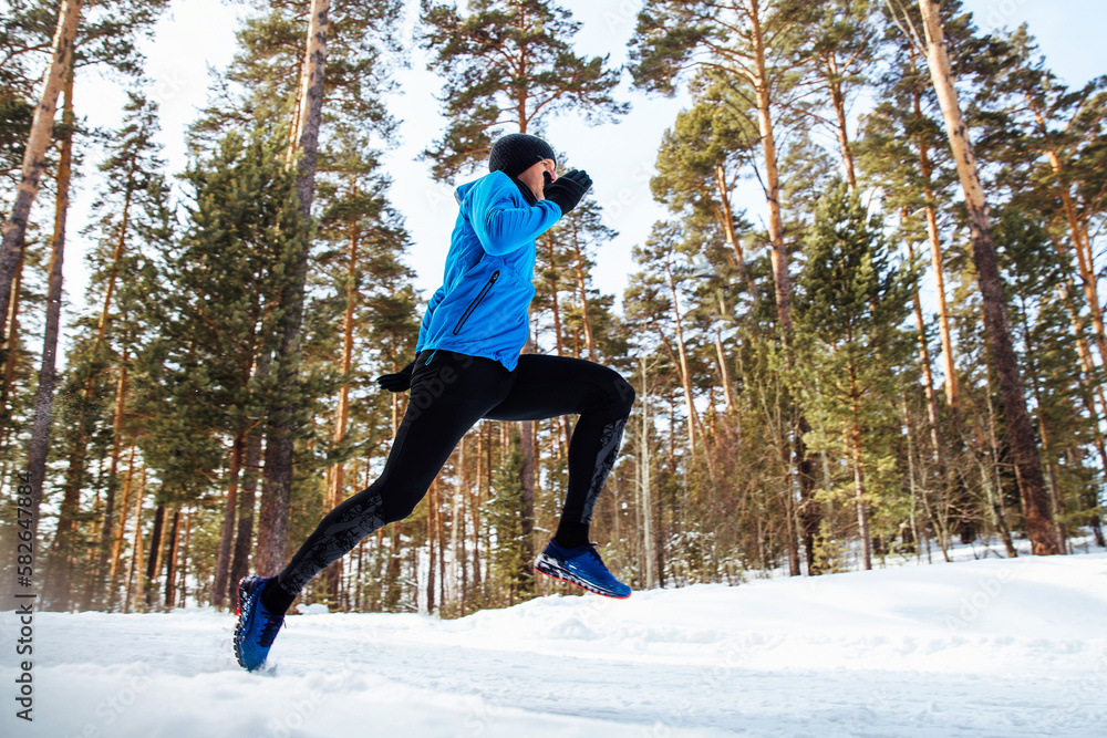 man jogger run winter forest trail in cold weather, side view, cross-country running
