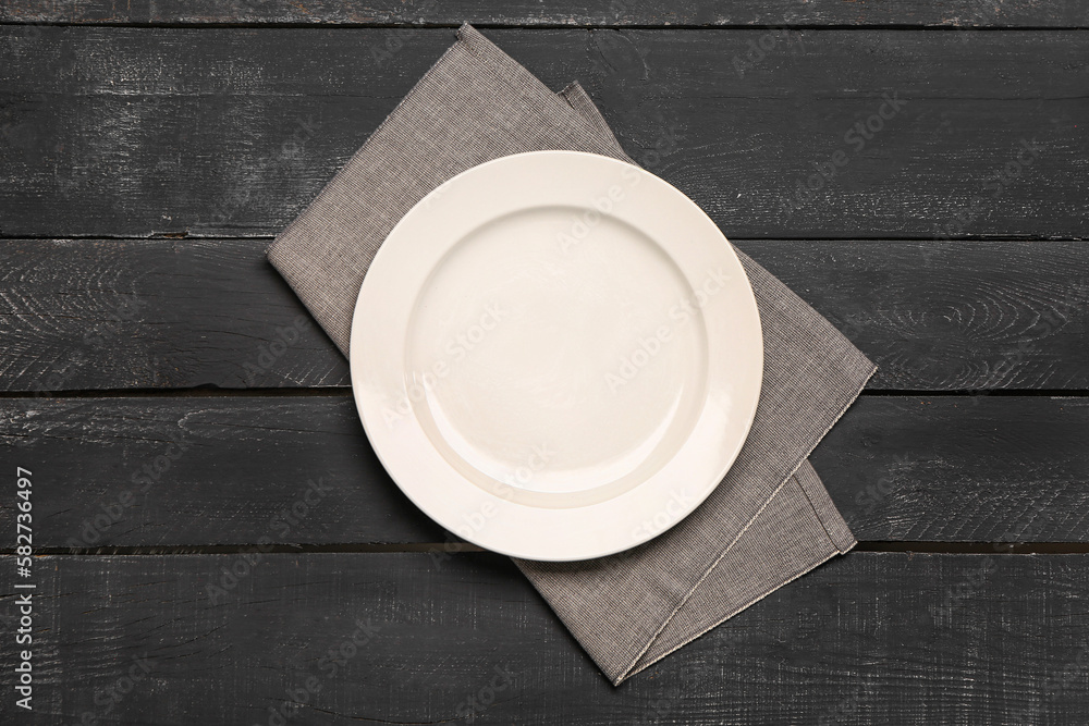Empty plate and napkin on dark wooden background