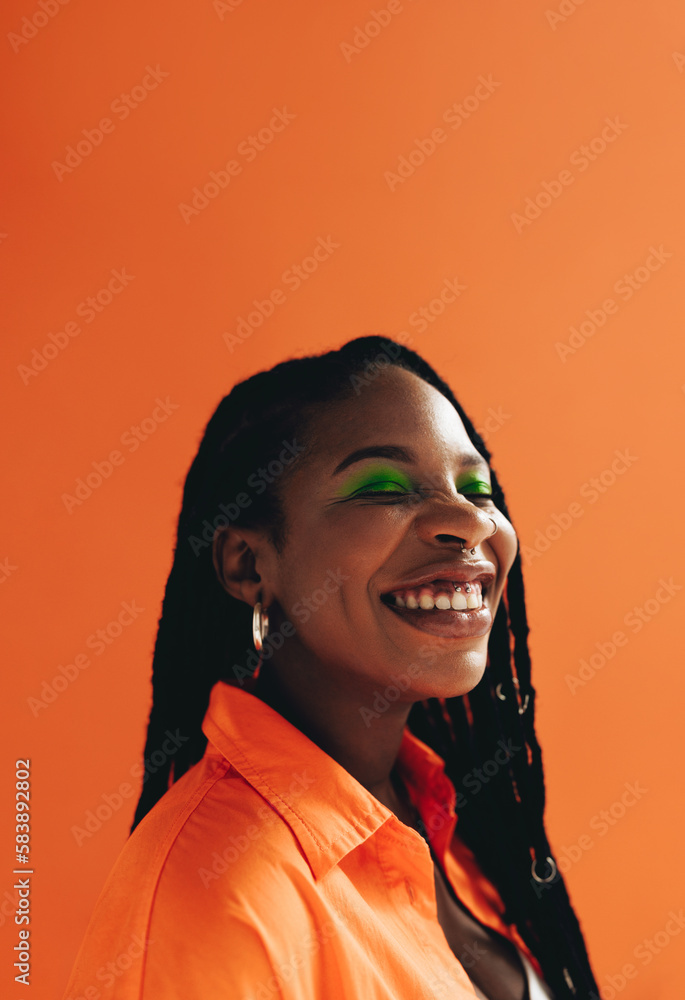 Cheerful african woman with makeup and face piercings smiling in a studio