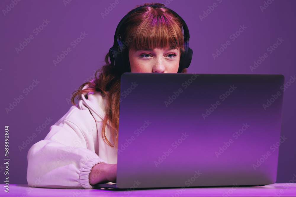 Female gamer focused while playing an online video game on her laptop