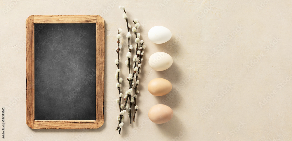 Easter composition with vintage Easter decorations and chalk board on beige stone background