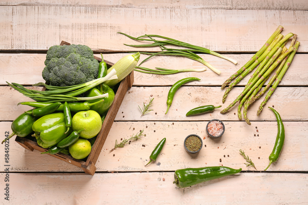 Composition with different fresh green vegetables in box on white wooden background